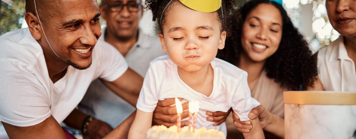 A young girl blows out birthday candles at her birthday party